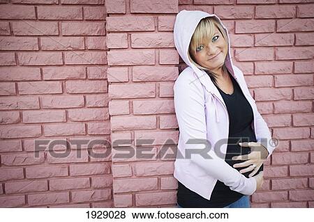 a young woman with her hands on her pregnant belly; edmonton, alberta, canada View Large Photo Image Stock Photo - a young woman with her hands on her pregnant belly; edmonton, alberta, canada. Fotosearch
