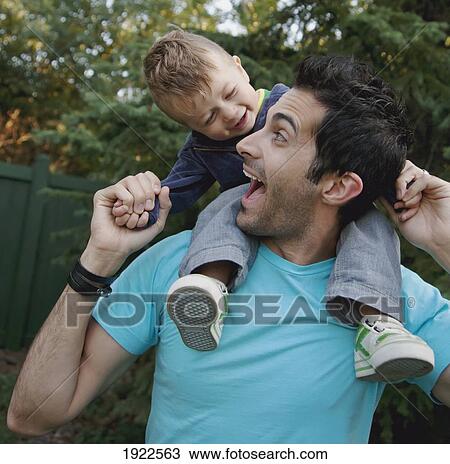 Stock Image - father and son smiling at each other; st. albert, alberta, canada. Fotosearch
