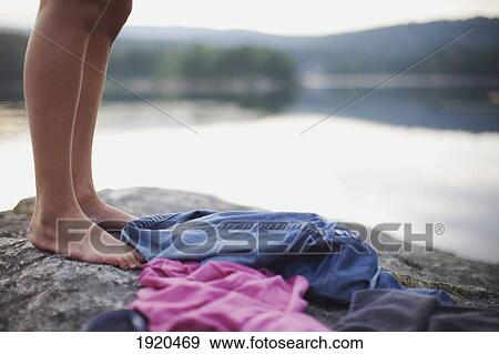 Stock Photo - feet and clothing on a rock by a lake; kristiansand, norway. Fotosearch