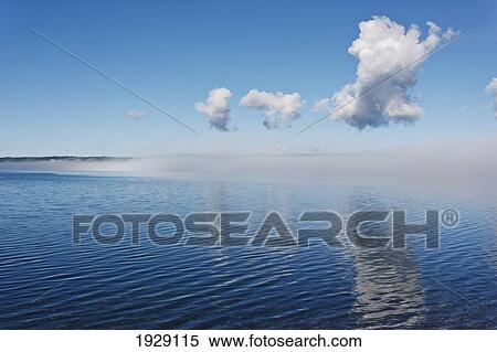 fog clearing from surface of lake to reveal blue water under blue sky; wyoming, united states of america View Large Photo Image Stock Photography - fog clearing from surface of lake to reveal blue water under blue sky; wyoming, united states of america. Fotosearch
