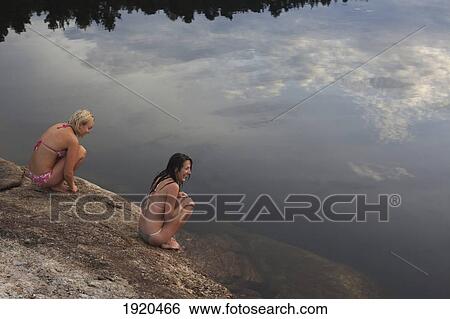 Stock Photograph - girls sitting by the lake after a swim; kristiansand, norway. Fotosearch