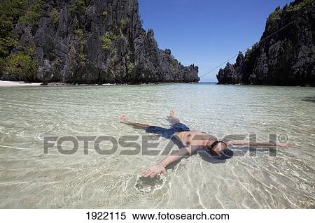 Stock Photography - man floating on his back in a lagoon; miniloc island, palawan, philippines. Fotosearch
