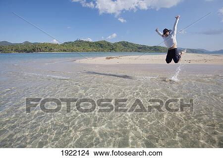 Picture - man jumping above the tropical water; bacuit archipelago, palawan, philippines. Fotosearch