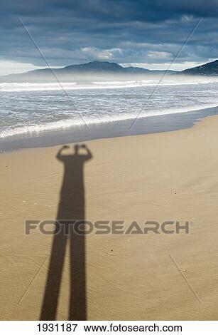 Stock Photo - shadow of a person with arms raised on the sand of los lances beach; tarifa, costa de la luz, cadiz, andalucia, spain. Fotosearch