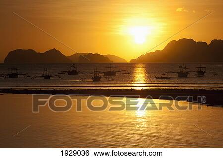 Stock Photograph - sunset view of islands and boats from the beaches of corong corong near el nido; bacuit archipelago, palawan, philippines. Fotosearch