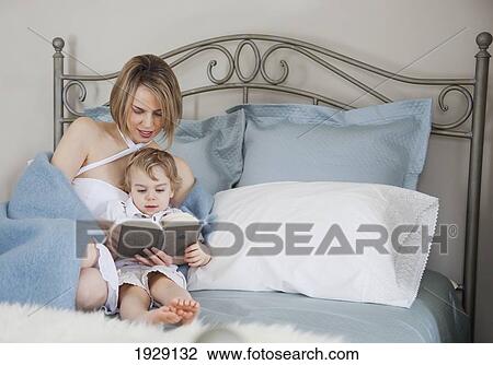 Stock Image - toddler and mother in bed reading; jordan, ontario, canada. Fotosearch