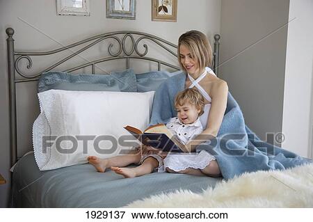 Stock Photo - toddler and mother in bed reading; jordan, ontario, canada. Fotosearch