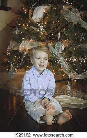 Stock Image - toddler sitting beside christmas tree. Fotosearch