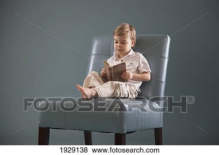 Stock Photo - toddler sitting in a big chair reading a book; jordan, ontario, canada. Fotosearch