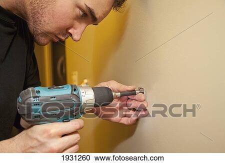 Stock Image - tradesman installing towel bar on wall. Fotosearch