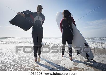 two young women carrying their surfboards on los lances beach; tarifa, cadiz, andalusia, spain View Large Photo Image Stock Photo - two young women carrying their surfboards on los lances beach; tarifa, cadiz, andalusia, spain. Fotosearch