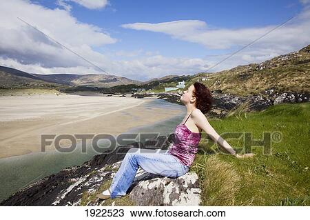 Stock Image - woman relaxing at beach; derrynane beach, county kerry, ireland. Fotosearch