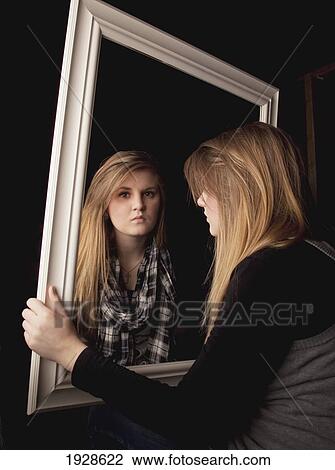 Stock Image - young woman seeing herself in a mirror. Fotosearch