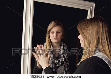 Stock Image - young woman seeing herself in a mirror. Fotosearch