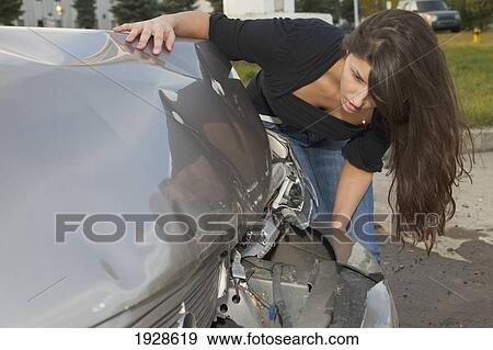 Stock Photo - young woman with vehicle that has been in a collision; edmonton, alberta, canada. Fotosearch