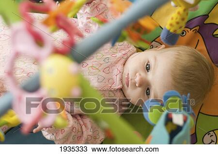 Stock Image - A Baby Laying On Her Back Looking Up At Her Hanging Toys; Alberta, Canada. Fotosearch