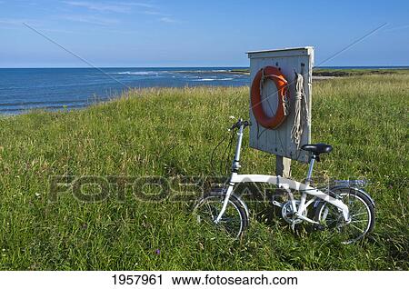 Stock Image - a bike leans on a wooden structure in the grass holding a buoy along the coast; northumberland england. Fotosearch