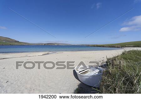 Stock Image - A Boat Abandoned On A Beach Along The Coast; Shetland Scotland. Fotosearch