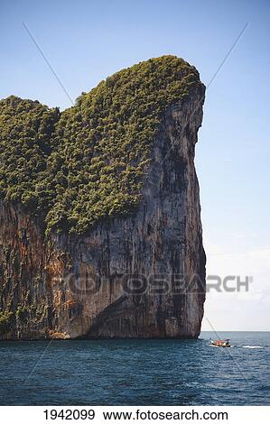 Stock Photo - A Boat Approaching One Of The Phi Phi Islands; Phuket Thailand. Fotosearch