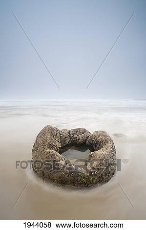 A Boulder With A Hole In The Middle Filled With Water On A Beach; Moeraki South Island New Zealand View Large Photo Image Stock Photo - A Boulder With A Hole In The Middle Filled With Water On A Beach; Moeraki South Island New Zealand. Fotosearch