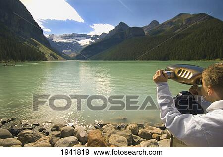 A Boy Looking Through Binoculars At A View Of The Mountains Over Lake Louise; Alberta Canada View Large Photo Image Stock Photo - A Boy Looking Through Binoculars At A View Of The Mountains Over Lake Louise; Alberta Canada. Fotosearch