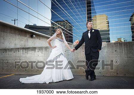 A Bride And Groom Posing In Front Of A Mirrored Building; Edmonton Alberta Canada View Large Photo Image Stock Image - A Bride And Groom Posing In Front Of A Mirrored Building; Edmonton Alberta Canada. Fotosearch