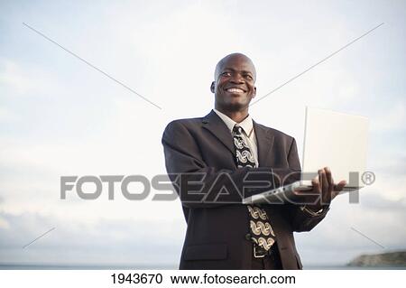 A Businessman Using A Laptop Computer By The Water; South Caicos Turks And Caicos Islands View Large Photo Image Stock Image - A Businessman Using A Laptop Computer By The Water; South Caicos Turks And Caicos Islands. Fotosearch