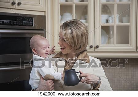 A Businesswoman Holding Her Baby In The Kitchen At Home; Jordan Ontario Canada View Large Photo Image Stock Image - A Businesswoman Holding Her Baby In The Kitchen At Home; Jordan Ontario Canada. Fotosearch
