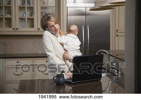 A Businesswoman With A Baby Working On The Computer And Talking On The Phone; Jordan Ontario Canada View Large Photo Image Stock Photography - A Businesswoman With A Baby Working On The Computer And Talking On The Phone; Jordan Ontario Canada. Fotosearch
