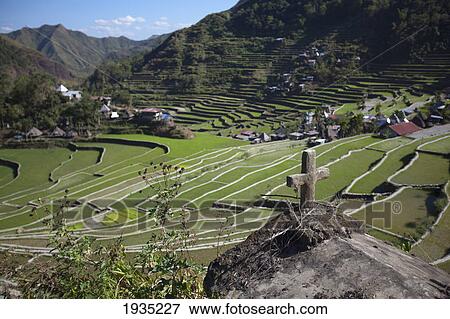 Stock Photo - A Cross Sits On A Ledge Over The Stunning Ifugao Stone-Walled Rice Terraces Surround The Village Of Batad; North Luzon, Philippines. Fotosearch