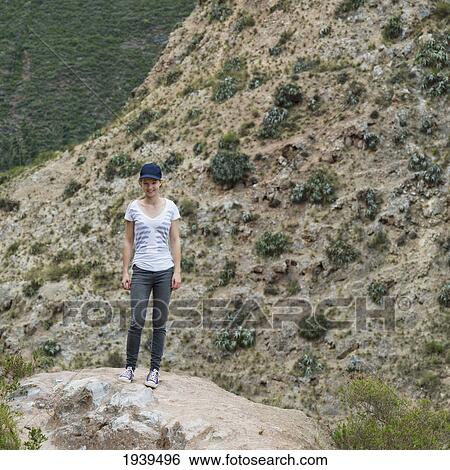 A Girl Standing On A Rock Beside A Mountain; Sacred Valley Peru View Large Photo Image Stock Photograph - A Girl Standing On A Rock Beside A Mountain; Sacred Valley Peru. Fotosearch