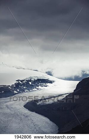 Stock Photograph - A Glacier Flowing Between Two Mountains; Banff Alberta Canada. Fotosearch