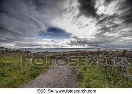 Picture - a gravel path leading to the ocean with stone walls on holy island; lindesfarne northumberland england. Fotosearch