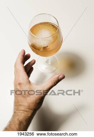 Stock Photograph - A Hand Reaching For A Glass Of Alcoholic Drink; Benalmadena Costa Malaga Andalusia Spain. Fotosearch