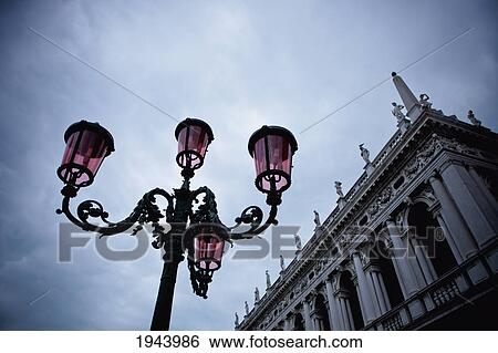 Stock Photograph - A Light Standard And An Ornate Building With Sculptures Lining The Roof; Venice Venezia Italy. Fotosearch