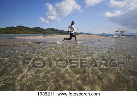 A Male Tourist Runs Through The Tropical Water At A Sandbar Island Near El Nido; Bacuit Archipelago, Palawan, Philippines View Large Photo Image Stock Image - A Male Tourist Runs Through The Tropical Water At A Sandbar Island Near El Nido; Bacuit Archipelago, Palawan, Philippines. Fotosearch