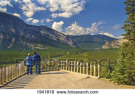 Stock Photo - A Man And Woman Overlooking A Scenic View Of Banff National Park; Banff Alberta Canada. Fotosearch