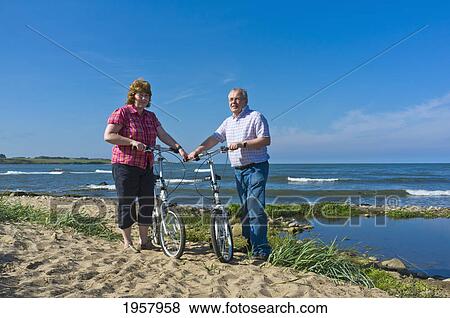 Stock Photo - a man and woman with their bicycles on the beach; northumberland england. Fotosearch