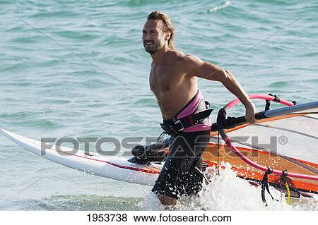 a man comes walks in the water with his windsurfing equipment; tarifa cadiz andalusia spain View Large Photo Image Stock Photo - a man comes walks in the water with his windsurfing equipment; tarifa cadiz andalusia spain. Fotosearch