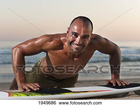 Stock Photograph - a man leaning on his surfboard on the beach; tarifa cadiz andalusia spain. Fotosearch
