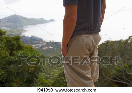 Stock Image - A Man Looks Down On A Tropical Island; Koh Tao Thailand. Fotosearch