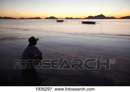 Stock Photo - A Man On A Beach At Sunset; Corong-Corong, Palawan, Philippines. Fotosearch