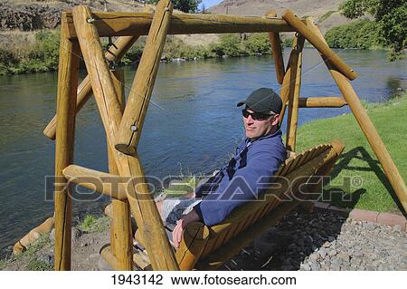 A Man Sitting On A Swing At The Water's Edge; Maupin Oregon United States Of America View Large Photo Image Stock Image - A Man Sitting On A Swing At The Water's Edge; Maupin Oregon United States Of America. Fotosearch