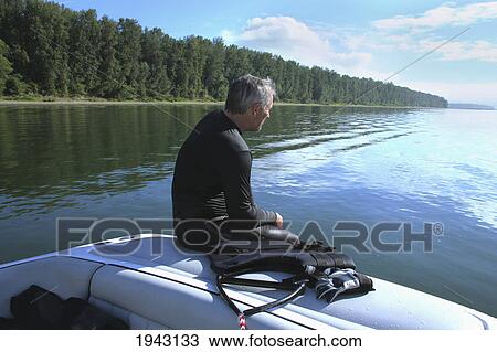Stock Image - A Man Sitting On The Back Of A Boat With A Life Jacket; Troutdale Oregon United States Of America. Fotosearch