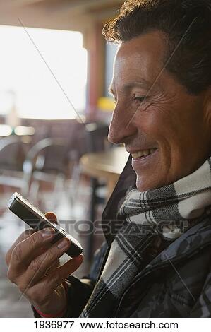 A Man Smiles As He Looks At His Cell Phone; Tarifa Cadiz Andalusia Spain View Large Photo Image Stock Photo - A Man Smiles As He Looks At His Cell Phone; Tarifa Cadiz Andalusia Spain. Fotosearch