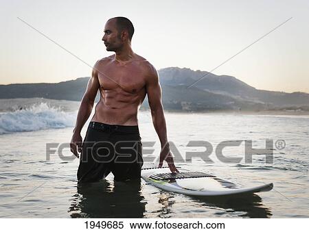 a man standing in the water with his surfboard off valdevaqueros beach; tarifa cadiz andalusia spain View Large Photo Image Stock Photography - a man standing in the water with his surfboard off valdevaqueros beach; tarifa cadiz andalusia spain. Fotosearch