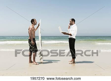 a man standing on a beach representing himself with a surfboard on vacation and working as a businessman; tarifa cadiz andalusia spain View Large Photo Image Stock Image - a man standing on a beach representing himself with a surfboard on vacation and working as a businessman; tarifa cadiz andalusia spain. Fotosearch