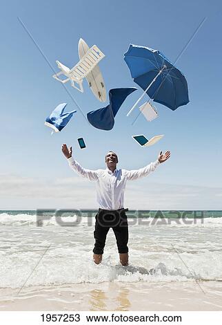 a man stands in the ocean with items from work and vacation flying over his head; tarifa cadiz andalusia spain View Large Photo Image Stock Image - a man stands in the ocean with items from work and vacation flying over his head; tarifa cadiz andalusia spain. Fotosearch
