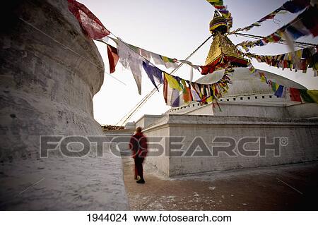 Picture - A Man Walking Amongst The Buildings With Prayer Flags Hanging Above; Kathmandu Nepal. Fotosearch