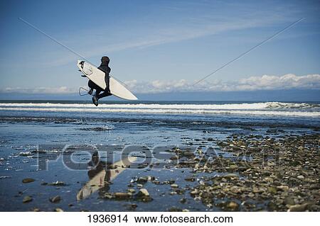 Picture - A Man Walks With His Surfboard Down The Beach; Washington Peninsula Washington United States Of America. Fotosearch